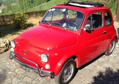 Red Fiat 500 with sunroof open on a sunny day