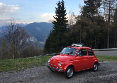 Red Fiat 500 parked in mountain with the sunroof open