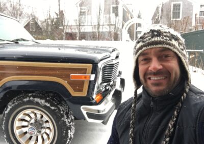 Man smiling in front of a Jeep Grand Wagoneer in deep snow