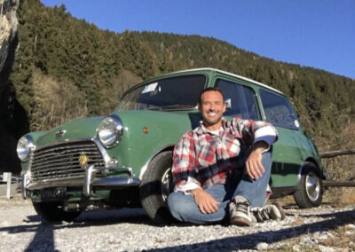 Man sitting on ground in front of a green Austin Mini-matic