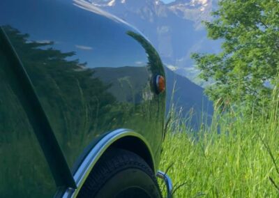 Closeup shot of a green Austin Mini-matic front side, reflecting the mountains