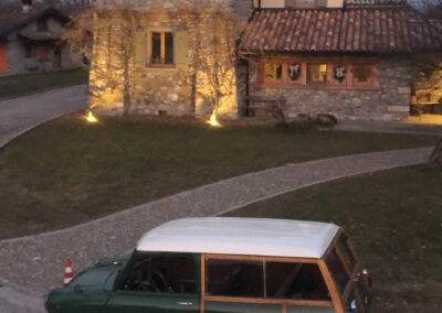 A green classic Mini Traveller parked in front of a house in the mountains