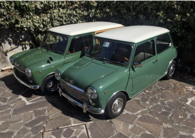Two green MINIs parked side by side, an Innocenti Mini t and an Austin Mini-matic