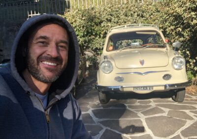 Man smiling in front of a beige classic NSU Prinz car