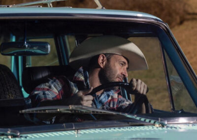 Man driving Jeep Kaiser Wagoneer in cowboy hat