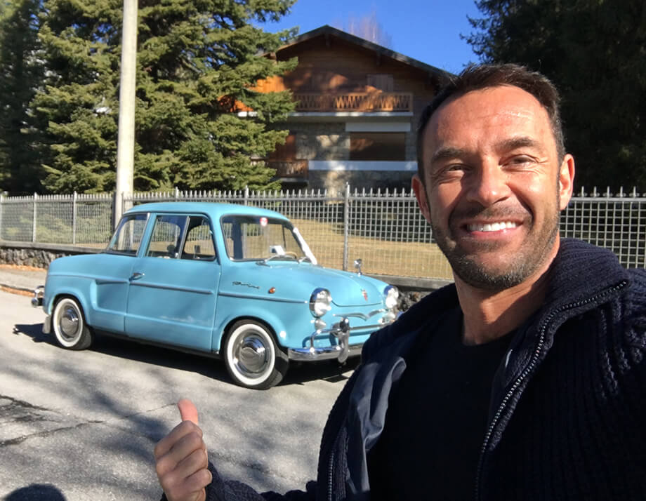 Man smiling in front of a baby blue NSU Prinz