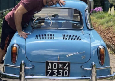 Man smiling while leaning over a baby blue classic NSU Prinz